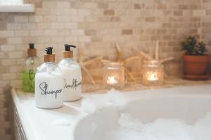 two bottles of soap sitting on a bathroom sink at Waves - Duplex Apartment Stoke Fleming in Stoke Fleming