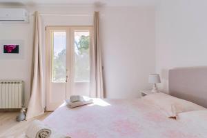 una camera bianca con un grande letto e una finestra di Garden view near the sea a Lecce