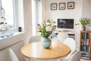 a dining room table with a vase of flowers on it at Waves - Duplex Apartment Stoke Fleming in Stoke Fleming