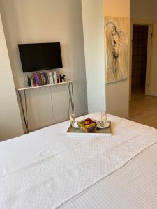 a tray of fruit on a bed with a television at B. Equine Range Hotel in Narlıdere