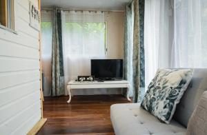 - un salon avec une télévision et un canapé blanc dans l'établissement sur la route du voile meublé hibiscus, à Salazie
