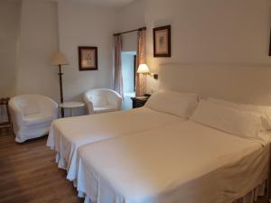 a bedroom with a large white bed and two chairs at Molino Del Santo in Benaoján