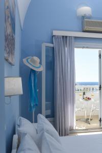 - une chambre avec un lit doté d'un chapeau sur une fenêtre dans l'établissement Glaros Hotel, à Kamari