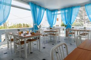 a restaurant with blue curtains and tables and chairs at Glaros Hotel in Kamari