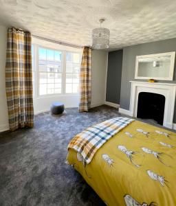 a bedroom with a yellow bed and a fireplace at Gigi's Place in Weymouth
