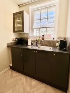 a kitchen with black cabinets and a sink and a window at Gigi's Place in Weymouth