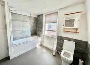 a bathroom with a tub and a toilet and a window at Gigi's Place in Weymouth