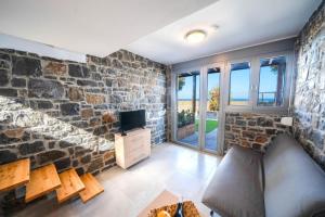 salon z kamienną ścianą i telewizorem w obiekcie TerraZeus - Stone House Beachfront 1 w mieście Milatos