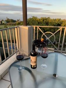Dois copos de vinho numa mesa de vidro na varanda em Ocean Life em Plettenberg Bay
