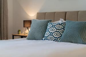 uma cama com almofadas azuis em cima em Content-Living em Cheltenham