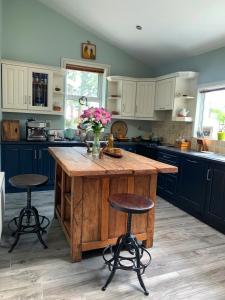 a kitchen with a large wooden island with two bar stools at Fortwilliam Farm T12DNN2 in Cork