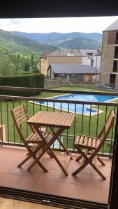 a picnic table and two chairs on a balcony with a pool at Precioso apartamento con piscina, ideal familias! in Sort