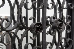 uma cerca de ferro preto com uma flor sobre ela em Liberte Apartments em Oradea