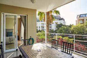 einen Balkon mit einem Tisch und Blick auf ein Gebäude in der Unterkunft Spacious Apartment Waterfront Fast WIFI in Kapstadt