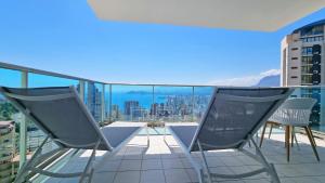 a balcony with two chairs and a view of the city at Apartamento con terraza privada y vistas al mar in Benidorm