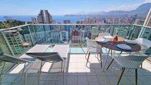 balkon ze stołem i krzesłami na dachu budynku w obiekcie Planta 21 Apartamento con terraza privada y vistas al mar w mieście Benidorm