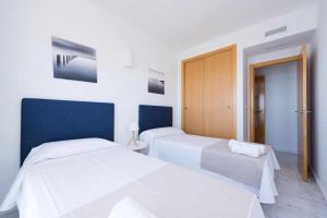 2 łóżka w pokoju z białymi ścianami i niebieskimi akcentami w obiekcie Planta 21 Apartamento con terraza privada y vistas al mar w mieście Benidorm