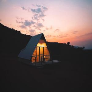 a small house with a sunset in the background at The Tribe Agrotourism, Wai mahabaleshwar in Panchgani