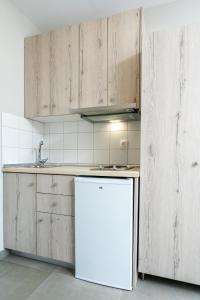 a kitchen with wooden cabinets and a white refrigerator at Atrium Hotel in Leptokarya