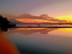 una puesta de sol en la playa con un reflejo en el agua en Tamarind Beach Bungalow, en Nusa Lembongan