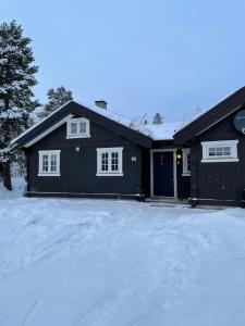 a black house with a garage in the snow at Hytte i nydelige Jotunhemen - rett ved Besseggen in Randsverk