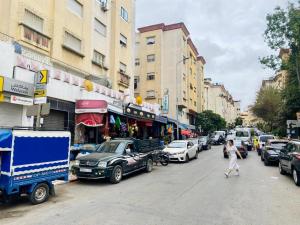 a woman walking down a city street with cars parked at Big appartment near soccer stadium in Tangier in Tangier