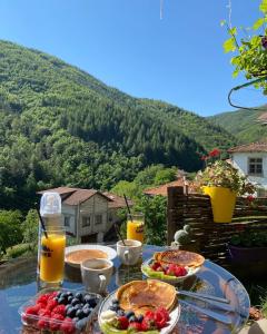 een tafel met pannenkoeken, fruit en jus d'orange bij Къща за гости Хаджиевата къща in Smolyan