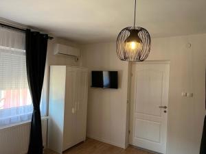 a room with a door and a television and a chandelier at 4 STARS ROOMS Near Airport in Ščitarjevo