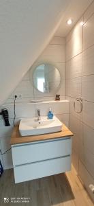 ein Bad mit einem Waschbecken und einem Spiegel in der Unterkunft Apartmenthaus Westerkoog in Hedwigenkoog