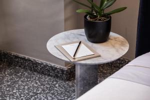 a table with a book and a potted plant on it at Rosselli AX Privilege in Valletta