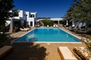 a swimming pool with lounge chairs and a house at Andromeda Residence in Mýkonos City