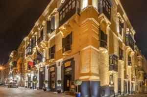 a yellow building on a street at night at Rosselli AX Privilege in Valletta