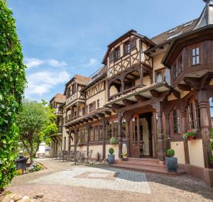 an old house with a courtyard in front of it at Hôtel au Heimbach in Lembach