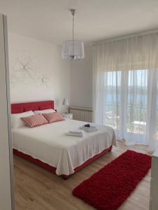 a white bedroom with a large bed with a red headboard at Apartman Betty in Šibenik