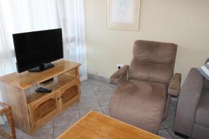 ein Wohnzimmer mit einem Flachbild-TV und einem Stuhl in der Unterkunft Corona Del Mar 13 in Margate