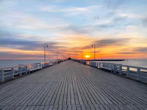a wooden pier with a sunset in the background at SeaSide Sopot - butikowe noclegi przy plaży in Sopot