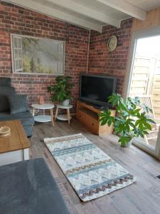 a living room with a brick wall and a television at Spatzennest 