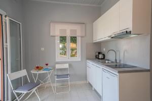 a kitchen with white cabinets and a table and chairs at Mary's Studios & Apartment in Sami