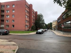 a street with cars parked in front of a building at Seaside Park in Liepāja