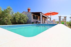 - une piscine d'eau bleue en face d'une maison dans l'établissement Holiday Home Zule, à Žrnovo