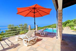 a patio with a red umbrella and two chairs and a pool at Holiday Home Zule in Žrnovo