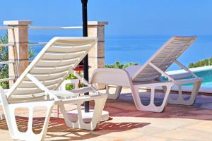 two white lawn chairs sitting on a patio with the ocean at Holiday Home Zule in Žrnovo