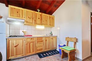 a kitchen with wooden cabinets and a table and a stool at Holiday Home Zule in Žrnovo