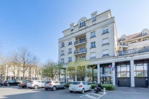 ブシー・サン ・ジョルジュにあるFamily Travel Parisの大きな白い建物と駐車場に駐車された車