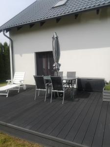 a deck with a table and chairs and an umbrella at Haus Am Meer in Mieroszyno