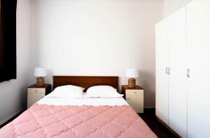 a bedroom with a pink bed with two white cabinets at Apartment Alkar in Sinj
