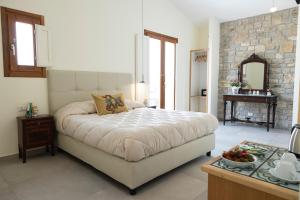 1 dormitorio con 1 cama grande y pared de piedra en La Corte del Sole en Calatafimi