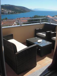 balcón con muebles de mimbre y vistas al agua en Apartmani Mia, en Trogir