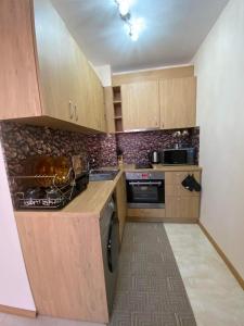 a small kitchen with wooden cabinets and a stove at Апартамент SUMI in Varna City