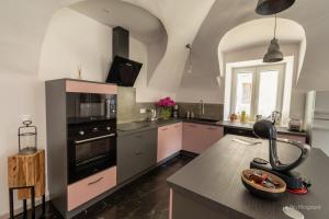 a kitchen with pink and black appliances and a table at Le Manoir, appartement Beryl in Le Bourg-dʼOisans